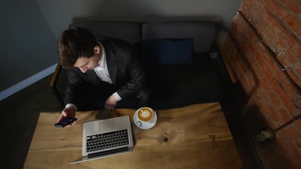 Geschäftsmann arbeitet am Laptop und trinkt Kaffee im Café. Ansicht von oben — Stockvideo