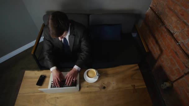 Dizüstü bilgisayarda çalışan ve kafe üzerinde kahve içme iş adamı. üstten görünüm — Stok video
