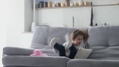 Küçük bir kız kanepede atlar