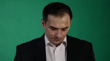 Yeşil arka plana karşı bir hayal kırıklığı jest yapıyor endişeli genç adam