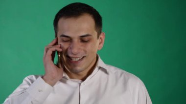 Cep telefonunu konuşan genç gülen adam. yeşil arka plan üzerinde izole. Genç adam konuşmak için cep telefonu