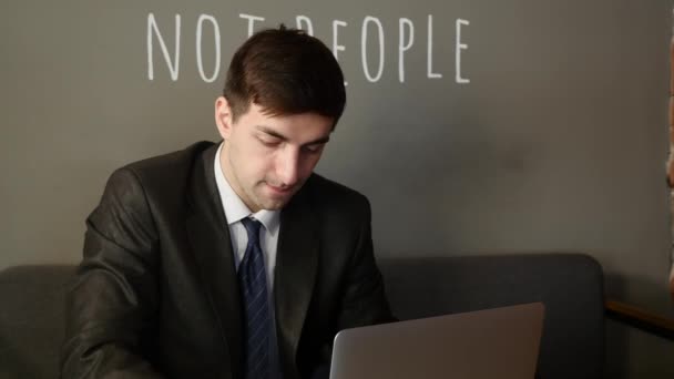 Νέος επιχειρηματίας που εργάζονται για το laptop και να μιλάμε με τον πελάτη, στο τραπέζι στην καφετέρια — Αρχείο Βίντεο