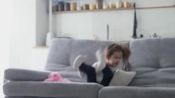 En liten flicka hoppar i soffan — Stockvideo