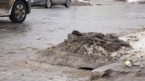 MOTION LENT, FERMER : L'eau trouble éclabousse la route asphaltée alors que la voiture roule dans la flaque d'eau. Sprays liquides marron à travers la rue noire — Video