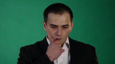 Yeşil arka plana karşı bir hayal kırıklığı jest yapıyor endişeli genç adam