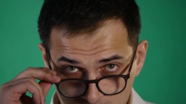 Baktılar hayrete erkek portresi yakından çenesi düştü kameraya benziyor, Gözlük, yeşil arka plan üzerinde izole dokunur