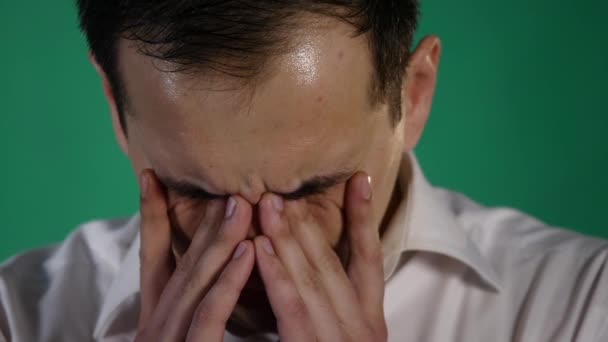 泣いている人のクローズ アップの肖像画。青年実業家は、緑の背景に涙で痛む目を閉じ — ストック動画