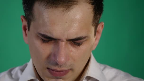 Ein trauriger junger Mann fängt an zu weinen, vor einem Studiohintergrund auf der grünen Leinwand. Nahaufnahme — Stockvideo