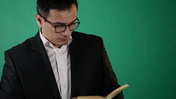 Jovem empresário com óculos lendo um livro sobre backgraund verde — Vídeo de Stock