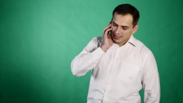 Mladý usměvavý muž mluví na jeho mobil. izolované na zeleném pozadí. Mladý muž mluví do mobilu — Stock video