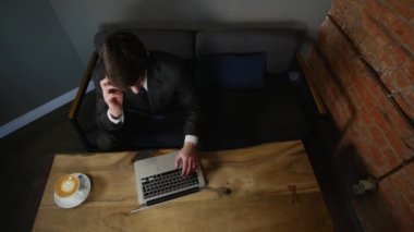 Kafede dizüstü kullanarak ve bitcoin ahşap masa üzerinde elinde tutan bir işadamı. üstten görünüm. zaman atlamalı