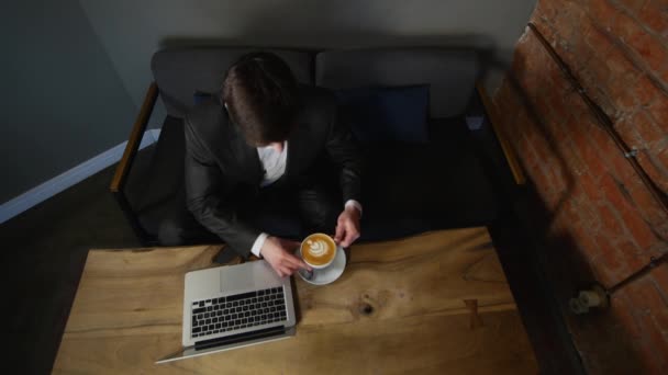 Uomo d'affari che lavora al computer portatile e beve caffe 'al caffe'. vista dall'alto — Video Stock