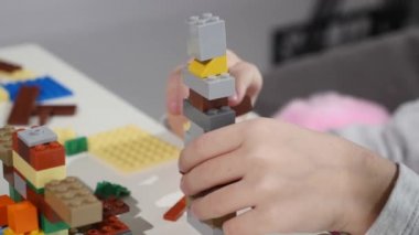 Childs'ın elleri bir küçük lego tuğla, Hands yakın Up oynamaya. LEGO inşaat oyuncak popüler bir çizgidir