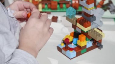 Childs'ın elleri bir küçük lego tuğla, Hands yakın Up oynamaya. LEGO inşaat oyuncak popüler bir çizgidir