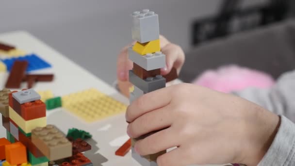Childs kezében egy kis lego tégla, szoros Hands Up játék. LEGO egy népszerű vonal építőjátékok — Stock videók