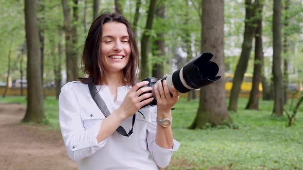 Mujer joven fotógrafa proceso de trabajo rodaje al aire libre en la naturaleza parque — Vídeos de Stock