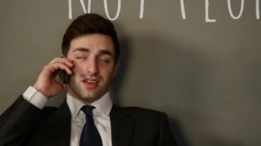 Genç çekici adam oturur konuşur telefon ve içme kahve Cafe