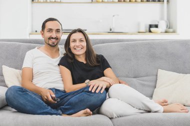 Kanepede oturan ve birlikte vakit Tv. genç bir aile izlerken sevgi dolu çift