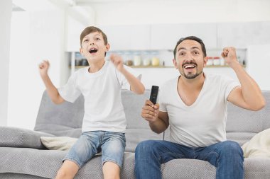 Baba ve oğul birlikte kanepe oturma ve futbol maçı izlerken