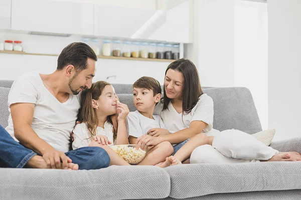 Szczęśliwe rodziny młodych jedzenie popcornu podczas oglądania tv w salonie — Zdjęcie stockowe