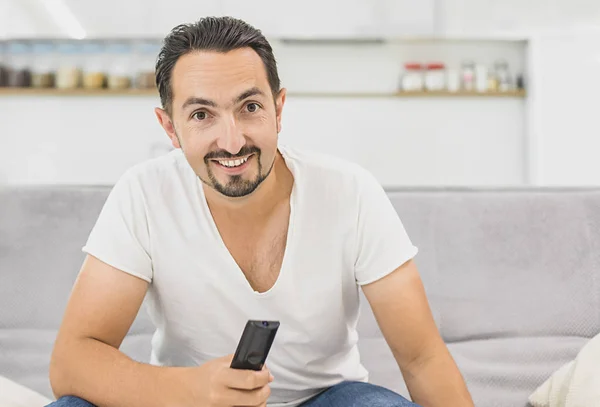home, technology and entretainment concept - smiling man with tv remote control at home