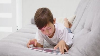 Sevimli çocuk kanepede tablet kullanırken rahatlatıcı