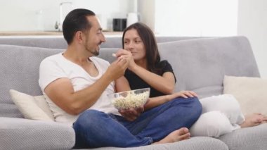 mutlu çift kanepe üzerinde patlamış mısır yiyor ve tv izle.