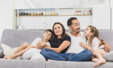 Modern daire arka plan kameraya gülümseyen kanepede oturan aile