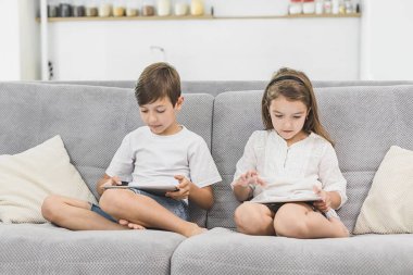 Becerikli alet iki çocuklu. Kız ve erkek kardeş net sörf ya da digital online oyun oynarken evde tablet. Modern iletişim ve gadget bağımlılık kavramı