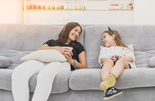 Мати і дочка сміються на сірому дивані вдома у вітальні — стокове фото