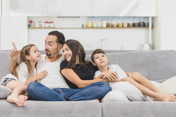 Happy family of four sitting on sofa. Happy family. Father, mother and children at home