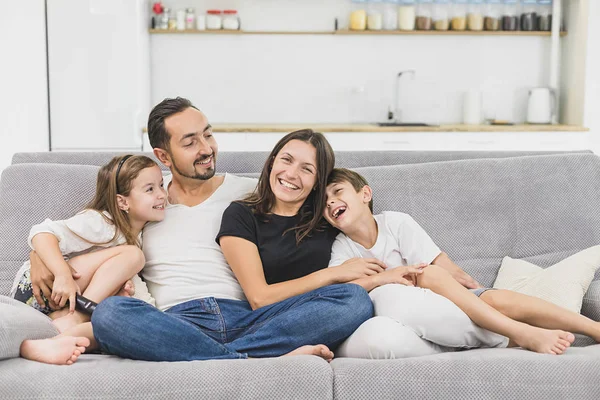 Happy family of four sitting on sofa. Happy family. Father, mother and children at home