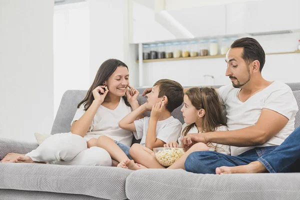 Feliz joven familia viendo película en casa con tazón de palomitas de maíz —  Fotos de Stock