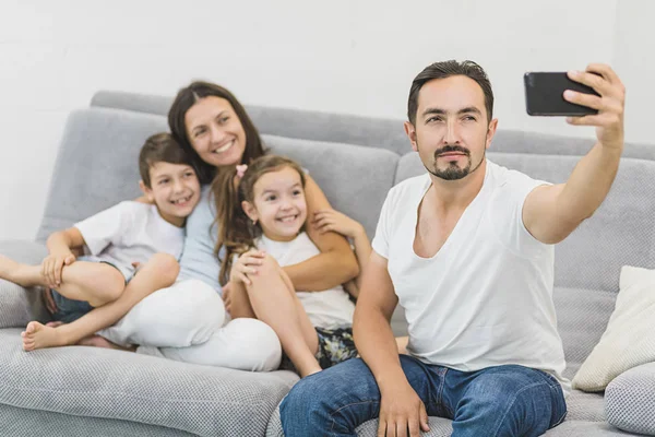 Rodzina klikając selfie siedząc na kanapie w domu — Zdjęcie stockowe
