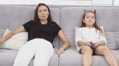 Anne ve kızı çok eğleniyorum ve oturma odasında kanepede oturup Tv izlerken konuşuyor