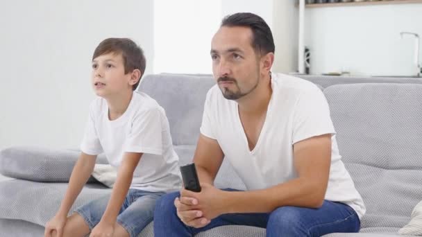 Un padre y un hijo celebran mientras ven un partido de fútbol — Vídeo de stock
