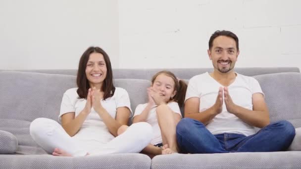 Милая счастливая семья аплодирует сидя на диване — стоковое видео