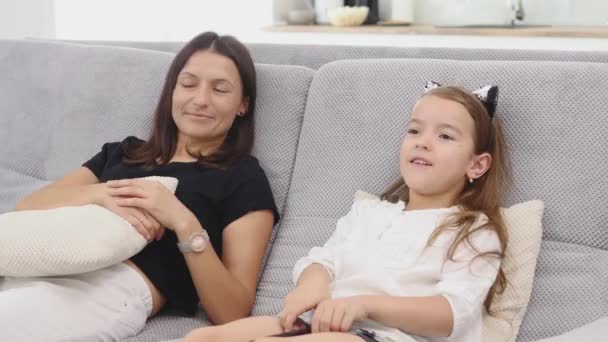 Matka a dcera mají spoustu legrace a mluví při sledování televize v obýváku na gauči