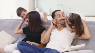 Televizyon izlerken koltukta oturan mutlu bir aile. Ebeveynler Tv seyretmek ve onların çocukları sinsice arkasında