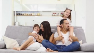 Gülümseyen genç ebeveynler ve çocukları çok mutlu, evdeler.