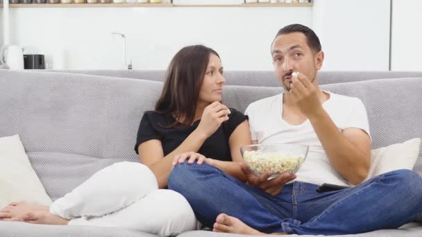 Młoda Para Trzymając Bowl Popcorn Jedzenia Mówienia Siedzieć Wygodną Sofę — Wideo stockowe