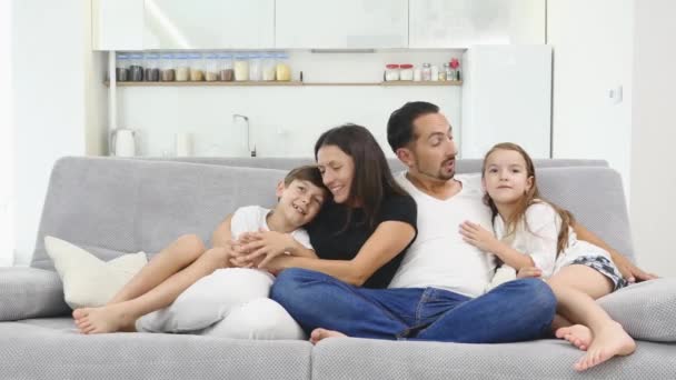 Счастливая семья сидит на диване и смотрит телевизор — стоковое видео