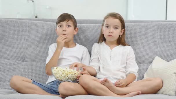 Niños felices viendo películas en casa y comiendo palomitas de maíz — Vídeos de Stock