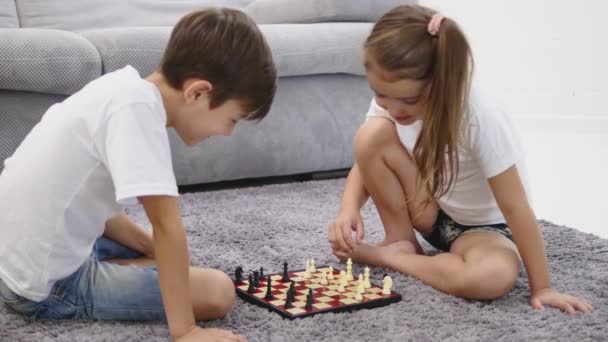 Two little children playing chess on the floor at home — Stock Video