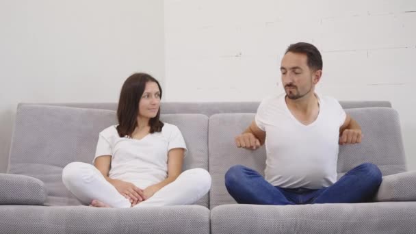 Улыбающаяся молодая пара отдыхает дома на диване — стоковое видео