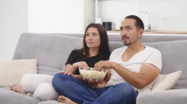 genç bir çift kanepede bir film izlerken patlamış mısır ile