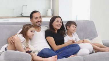 birlikte televizyon izlerken koltukta oturan iki çocuklu mutlu aile