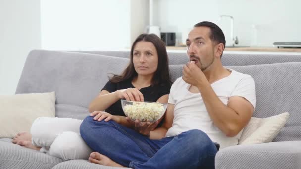 Paar schaut Film auf Couch beim Popcorn essen — Stockvideo