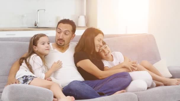 Familia sentada en un sofá en el salón viendo televisión juntos — Vídeo de stock
