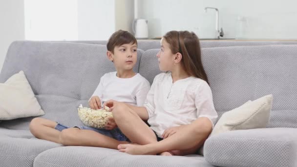 Enfants mignons regardant la télévision sur le canapé à la maison — Video